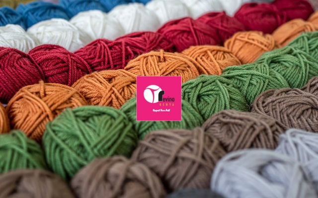 Close-up of colorful yarn balls arranged in rows with a pink logo card in the center.