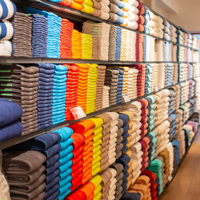 Shelves filled with neatly folded towels arranged in colourful and neutral rows.