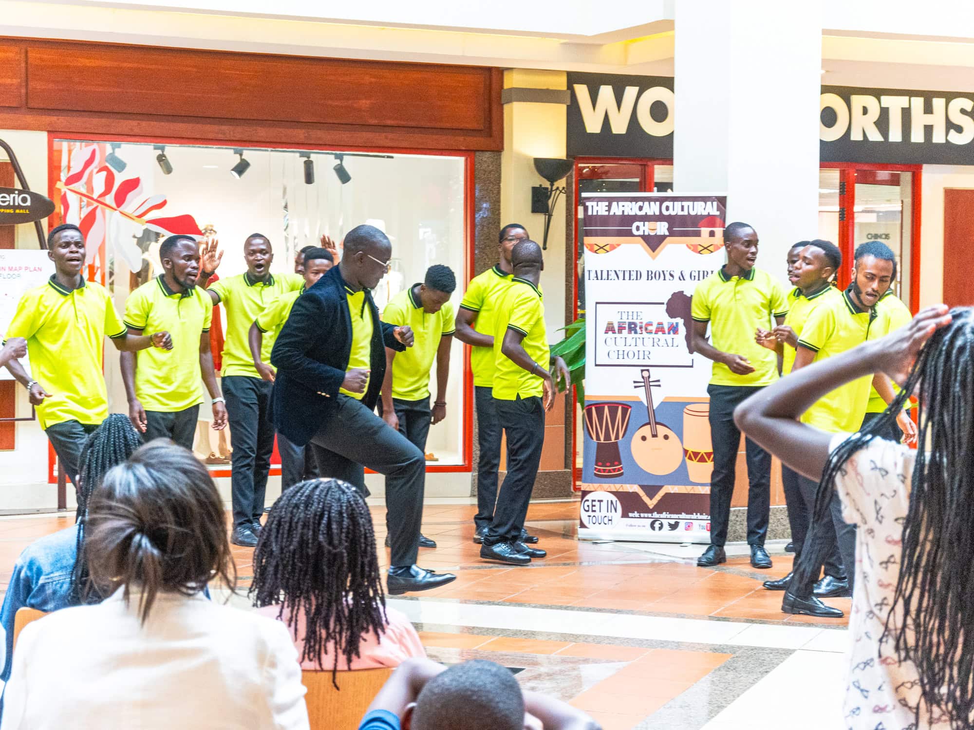 Men in lime green shirts perform in a shopping mall while people watch