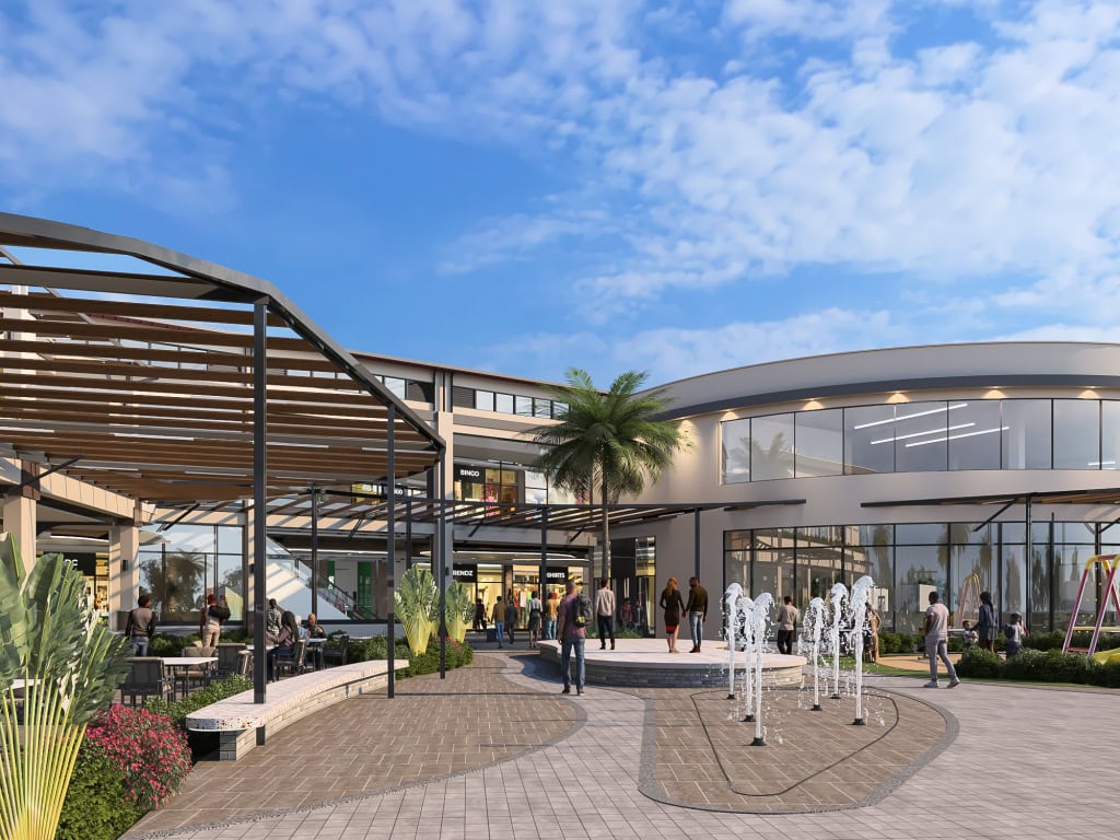 Outdoor shopping mall courtyard with fountains, palm trees, covered walkways, and visitors