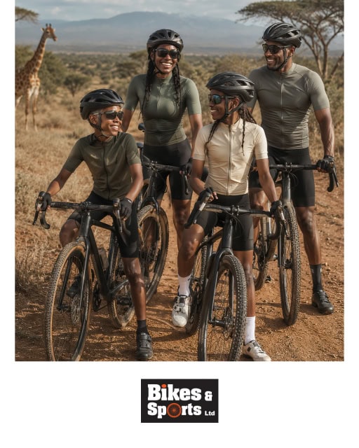 Four cyclists posing with their bicycles in a dry landscape with giraffes in the background