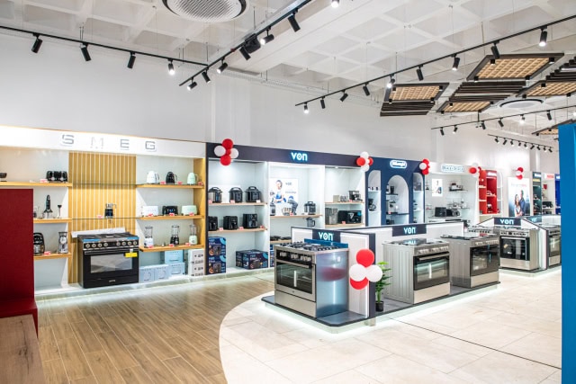Broad view of an appliance showroom with freestanding ovens, countertop appliances, and branded display bays.