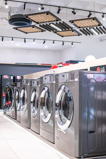 Row of stainless steel front-loading washing machines in an appliance showroom