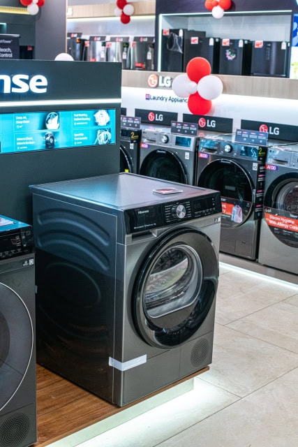 Dark front-loading washing machine displayed among rows of laundry appliances
