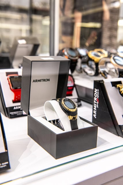 Black-and-gold wristwatch displayed in an open presentation box among other watches.