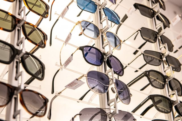Close-up of assorted sunglasses with dark and colored lenses on display