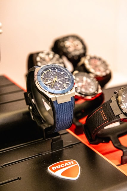 Blue-strap chronograph watch displayed on a Ducati-branded stand.