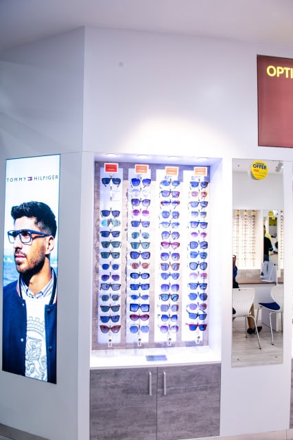 Rows of sunglasses displayed beside a Tommy Hilfiger eyewear advertisement inside the store