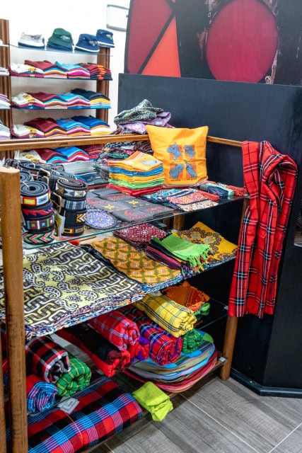 Retail interior with shelves and tables displaying colorful textiles, hats, bags and clothing