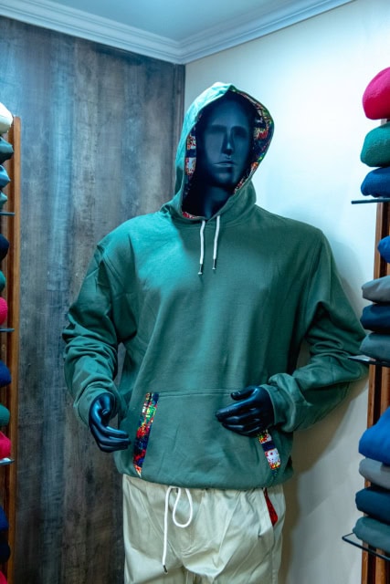 Mannequin wearing a green hooded sweatshirt with colorful patterned trim