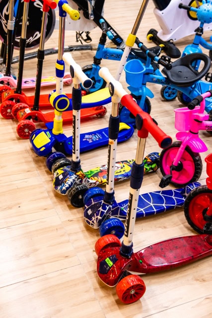 Colourful children's scooters arranged on the floor of a bicycle shop.