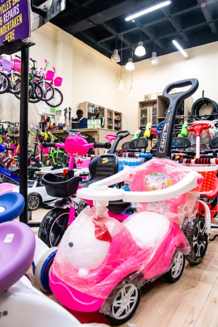 Bright retail store interior filled with bicycles, children's ride-on toys and accessories.