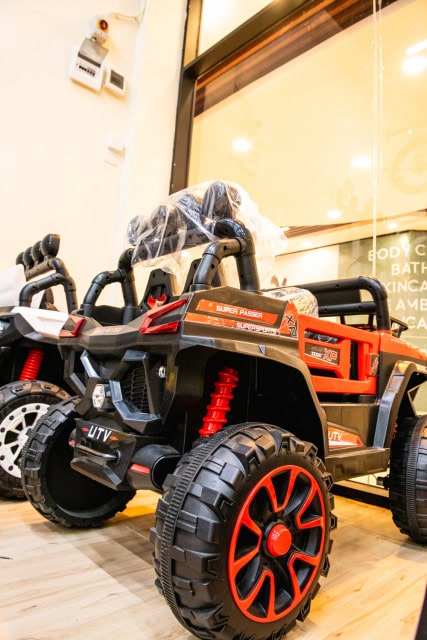 A red and black child-sized ride-on UTV with large tires displayed indoors