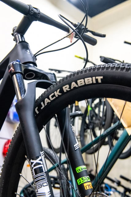 Close-up of a bicycle fork and Jack Rabbit branded tire among other bicycles