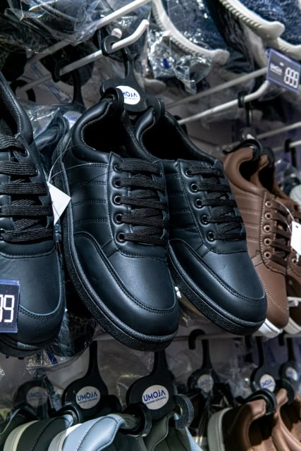 Black lace-up sneakers hanging on a footwear display rack