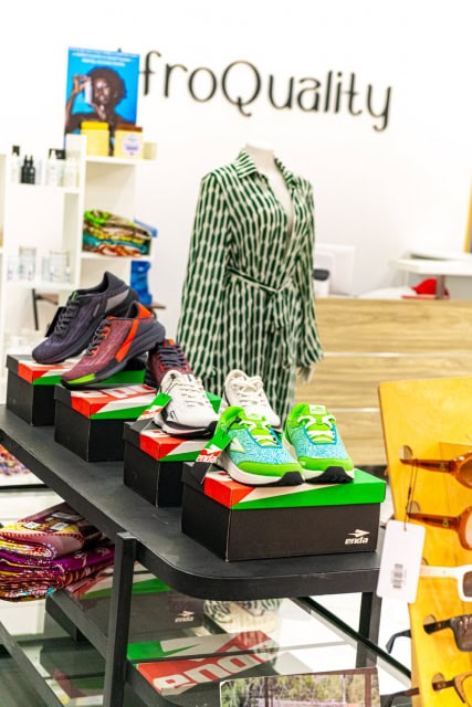 AfroQuality store interior with colorful shoes displayed on boxes beside a green patterned dress.