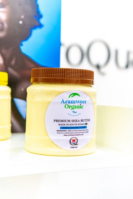 Yellow Aramweer Organic premium shea butter jar displayed on a white shelf.