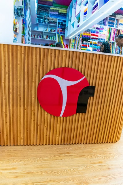 Wood-slat counter with a pink circular logo inside a craft shop