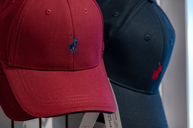 Close-up of a red embroidered baseball cap with a navy cap behind it