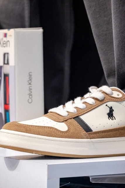 White and tan low-top sneaker with black detailing displayed on a shelf