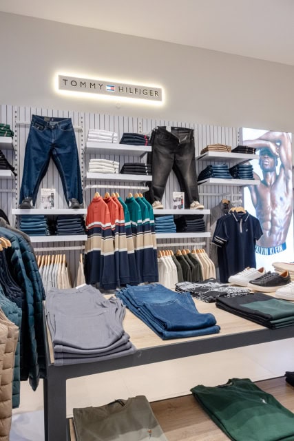 Wide view of a clothing store interior with denim, folded garments and shirts on display