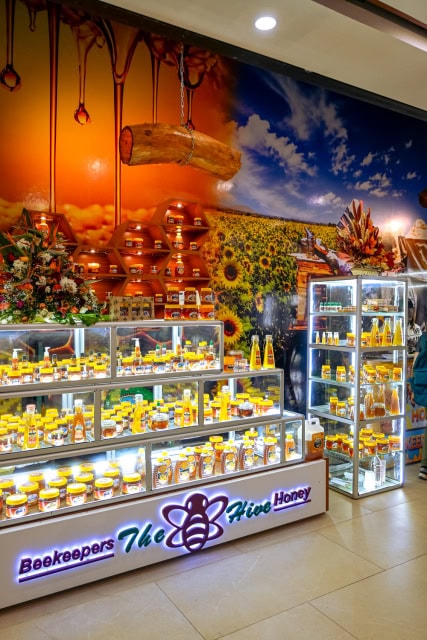 Illuminated honey retail kiosk with glass cabinets and a large wall mural