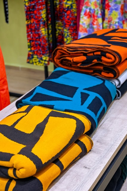 Folded orange, blue, yellow, and black graphic textiles on a display table