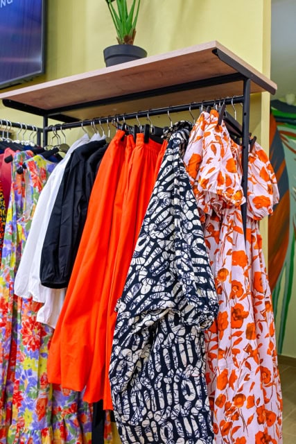 Clothing rack displaying bright orange, patterned, black, and floral garments