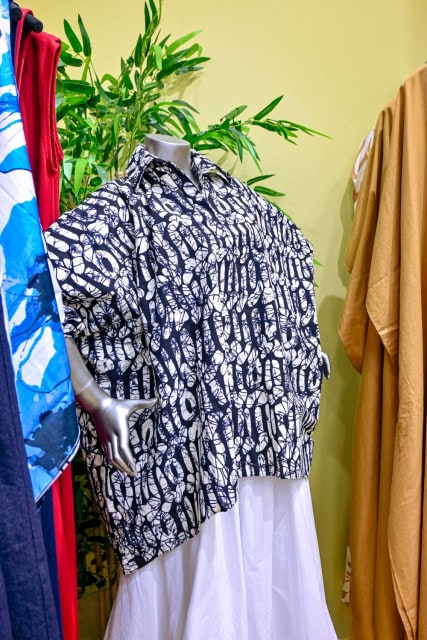 Mannequin wearing a dark patterned shirt and white skirt in a clothing store