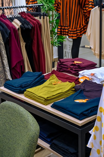 Table displaying neatly folded garments in teal, olive, burgundy, navy and white