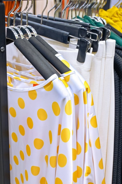 Close-up of white garments with large yellow dots on clothing hangers