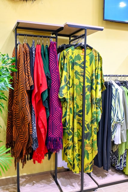 Display of colourful patterned garments and a green botanical-print dress