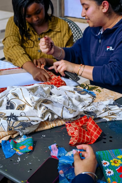 Workshop participants work together on a red patterned fabric frame at Galleria Shopping Mall.