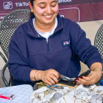 A smiling workshop facilitator works with fabric during the Frame and Fabric Workshop at Galleria.