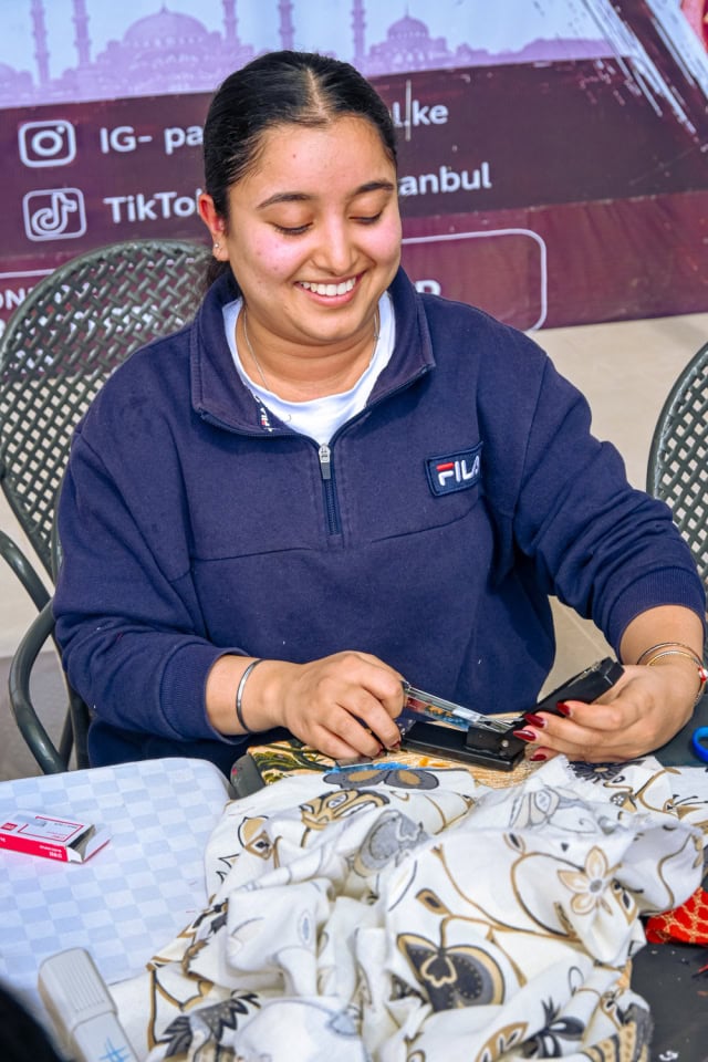 A smiling workshop facilitator works with fabric during the Frame and Fabric Workshop at Galleria.