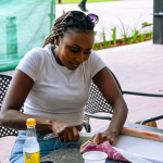 Participant carefully cuts fabric at a workshop table during the Frame and Fabric Workshop.