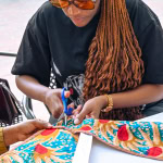 A workshop participant cuts colourful patterned fabric during the Frame and Fabric Workshop at Galleria.