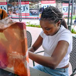 A participant assembles a large colourful fabric frame outside Galleria Shopping Mall during the workshop.