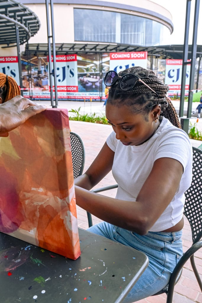 A participant assembles a large colourful fabric frame outside Galleria Shopping Mall during the workshop.