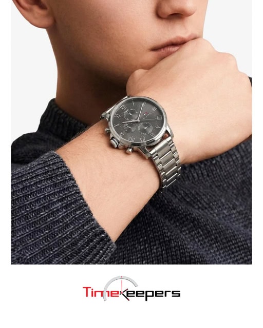 Lifestyle advertisement showing a silver chronograph wristwatch worn on a person’s wrist.