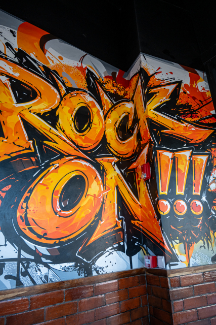 Large orange, black and white graffiti-style Rock On mural inside the restaurant