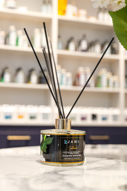 Black scented reed diffuser jar with several black reeds on a display table