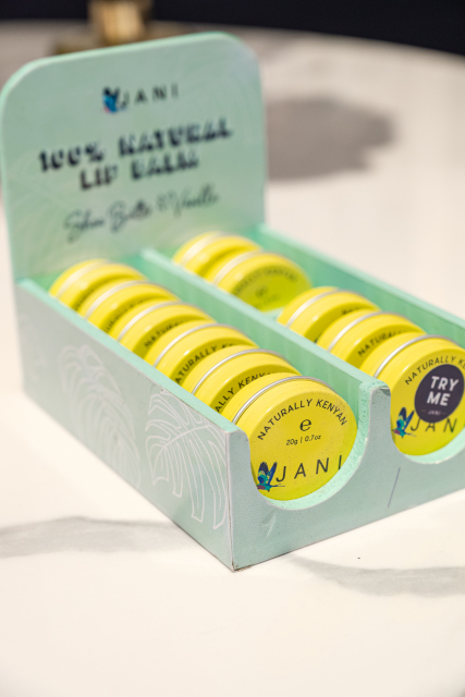 Mint-green JANI display tray filled with yellow-lidded natural lip balm tins.
