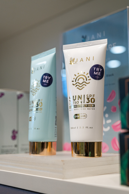 White and pale blue JANI sunscreen tubes displayed on a wooden retail shelf