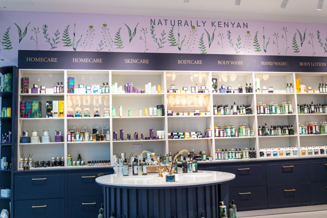 Wide view of a JANI retail interior with product shelves, category signs, a central display table, and botanical wall artwork
