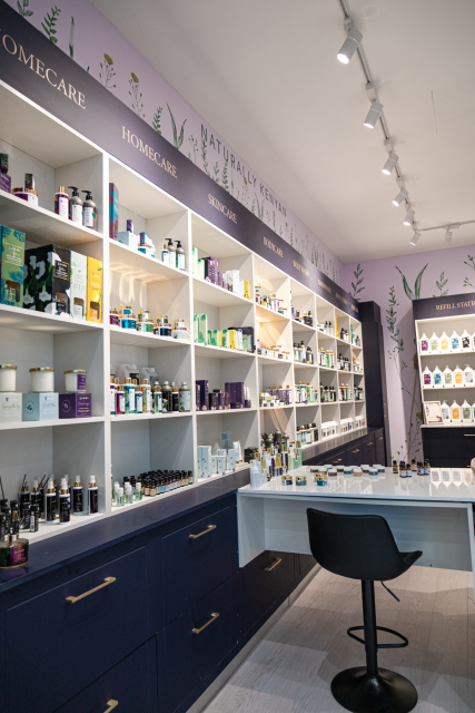 Interior of JANI Beauty showing product shelves, a counter, stool, and botanical wall decor