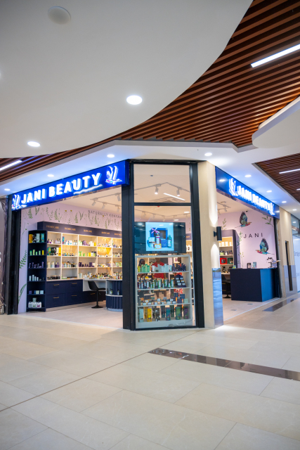 Angled view of the JANI BEAUTY corner storefront with a glass product display and open interior