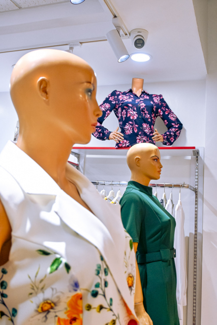Three mannequins displaying floral and solid-color outfits inside a clothing store