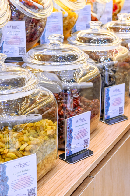 Glass jars of green and red dried foods displayed with product cards