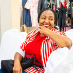 A smiling guest in a red-and-white striped jacket enjoys Style, Shop & Sip.